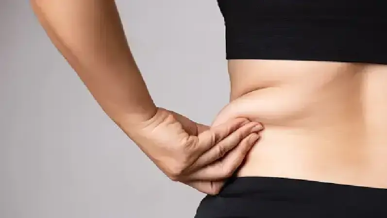 Woman holding her skin on the abdomen